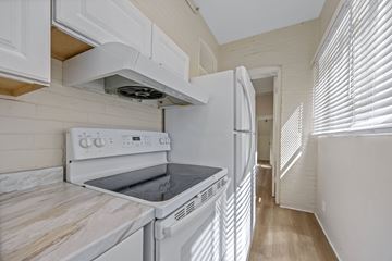 Denver apartment for rent - A white kitchen with a stove top oven and a refrigerator.