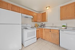 Denver apartment for rent - A kitchen with white appliances and wooden cabinets.