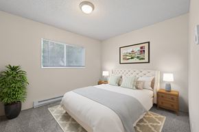 Denver apartment for rent - A bedroom with a large bed, a potted plant, and a painting on the wall.