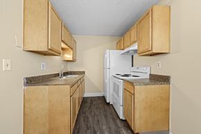 Commerce City apartment for rent - A kitchen with wooden cabinets and a white refrigerator.