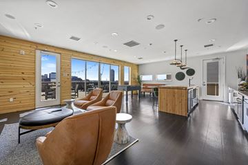 Denver apartment for rent - A modern living room with brown leather chairs and a wooden wall.