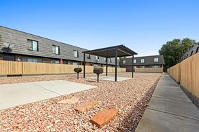 Longmont apartment for rent - A building with a wooden fence and a gravel area in front.