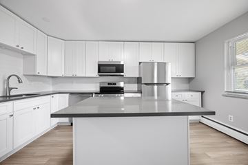 Boulder apartment for rent - A modern kitchen with white cabinets and a central island.