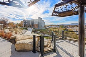 Arvada apartment for rent - A modern building with a glass facade is surrounded by a metal fence and a stone pathway.