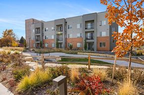 Arvada apartment for rent - A modern apartment complex with a landscaped courtyard in the foreground.