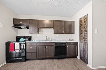 Lakewood apartment for rent - A kitchen with brown cabinets and black appliances.