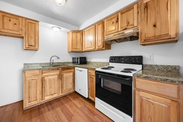Longmont apartment for rent - A kitchen with wooden cabinets and a white stove top oven.