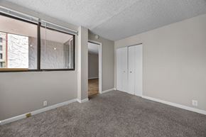 Boulder apartment for rent - A room with a carpeted floor, a window with a view of a building outside, and a white door.