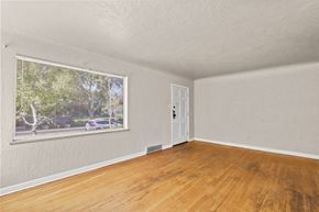 Denver apartment for rent - an empty living room with a large window and wooden floors