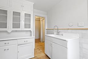 Denver apartment for rent - a kitchen with white cabinets and a sink and a door to a hallway