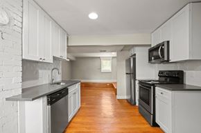 Boulder triplex for rent - A kitchen with white cabinets and a wooden floor.