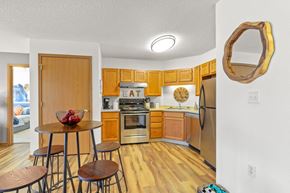 Greeley apartment for rent - a kitchen with wooden cabinets and stainless steel appliances and a table with three stools