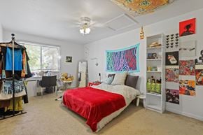 Boulder triplex for rent - Bedroom with a red bedspread and a large artwork on the wall.