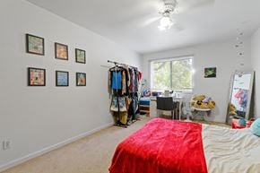 Boulder triplex for rent - A bedroom with a red bedspread and a clothing rack with clothes hanging on it.