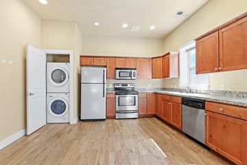 Denver apartment for rent - a kitchen with wood cabinets and stainless steel appliances and a washer and dryer