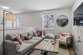 Boulder apartment for rent - A living room with a grey couch, a wooden coffee table, and a round mirror on the wall.