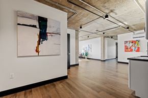 Greeley apartment for rent - A large painting hangs on a white wall in a spacious room with wooden floors and exposed ceiling beams.