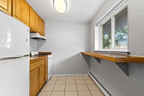 Denver apartment for rent - a kitchen with white appliances and wooden cabinets and a window