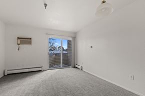 Longmont apartment for rent - A spacious, empty room with a sliding glass door leading to a backyard.
