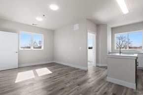 Denver apartment for rent - A spacious room with wooden floors and white walls.