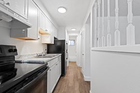 Denver apartment for rent - A long hallway with white walls and a black refrigerator.