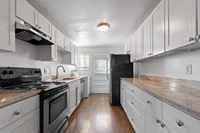 Denver apartment for rent - A kitchen with black appliances and white cabinets.