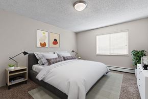 Denver apartment for rent - A bedroom with a large bed and a nightstand with a plant on it.