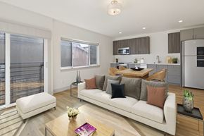 Denver apartment for rent - A modern living room with a couch, coffee table, and a kitchen area in the background.