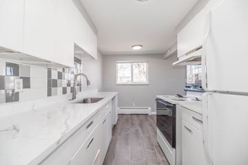 Denver apartment for rent - A modern kitchen with white cabinets and a marble countertop.