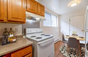 Lakewood apartment for rent - A kitchen with a stove top oven and a dining table with chairs.