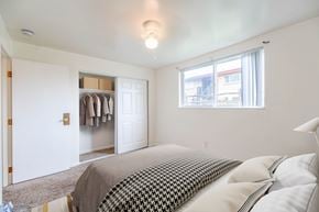 Lakewood apartment for rent - A bedroom with a bed, a window, and a closet with clothes hanging.