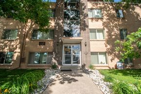Littleton apartment for rent - A building with a grey door and windows with white curtains.
