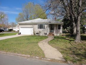 Denver apartment for rent - A house with a white garage door is surrounded by trees.