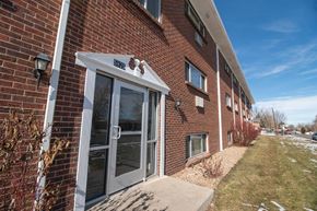 Commerce City apartment for rent - A brick building with a glass door and windows.