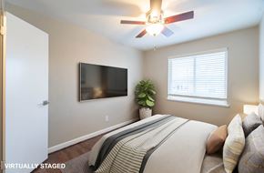 Edgewater apartment for rent - A bedroom with a bed, a ceiling fan, a television, and a window.