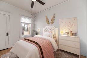 Denver apartment for rent - A bedroom with a white bed, a white dresser, and a ceiling fan.