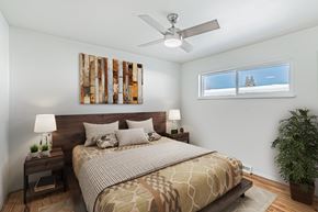 Wheat Ridge apartment for rent - A bedroom with a bed, nightstand, and a plant.