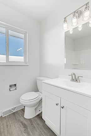 Wheat Ridge apartment for rent - A white bathroom with a toilet, sink, and mirror.