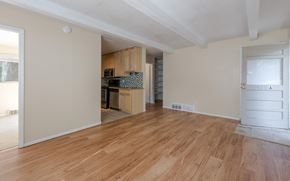 Boulder triplex for rent - A room with wooden flooring and a kitchen area in the background.