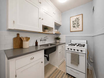 Denver apartment for rent - A kitchen with white cabinets and a white stove.