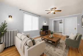 Denver apartment for rent - A living room with a beige couch, a green armchair, a wooden coffee table, and a ceiling fan.