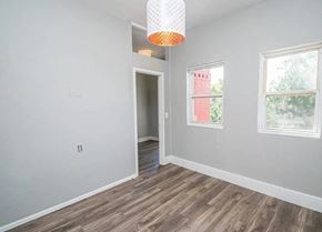 Denver apartment for rent - A room with a wooden floor and a window showing a red building outside.