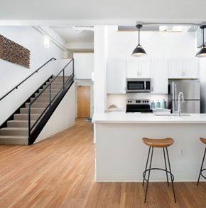 Denver apartment for rent - A kitchen with white cabinets and a bar area with stools.