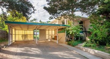 Boulder triplex for rent - A carport with a green roof is surrounded by trees and a house.