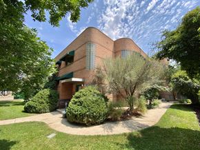 Denver apartment for rent - A large red brick building with a green awning and a circular driveway in front.