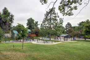 Boulder apartment for rent - A playground with swings and slides is surrounded by trees.