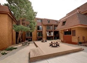 Boulder apartment for rent - A courtyard with a wooden deck and benches surrounded by brick buildings.