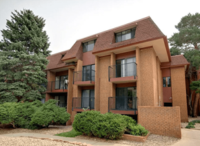 Boulder apartment for rent - A brick building with a balcony and a small garden in front.