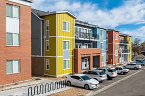 Greeley apartment for rent - A row of colorful apartment buildings with cars parked in front.