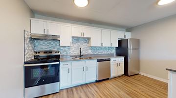Denver apartment for rent - A kitchen with white cabinets and a black stove top oven.